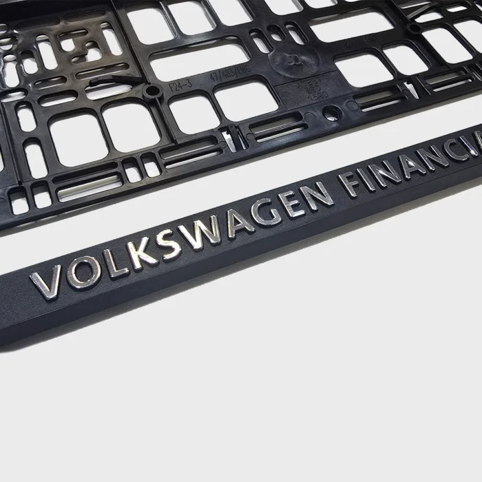 Nahaufnahme eines 3D-Schriftzugs mit glänzender Chromveredelung auf schwarzer Leiste