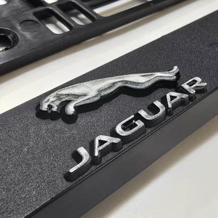 Detailansicht eines schwarzen Kennzeichenhalters mit erhabenem Jaguar-Logo in matter Folienveredelung